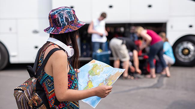 young woman reading a map next to a coach